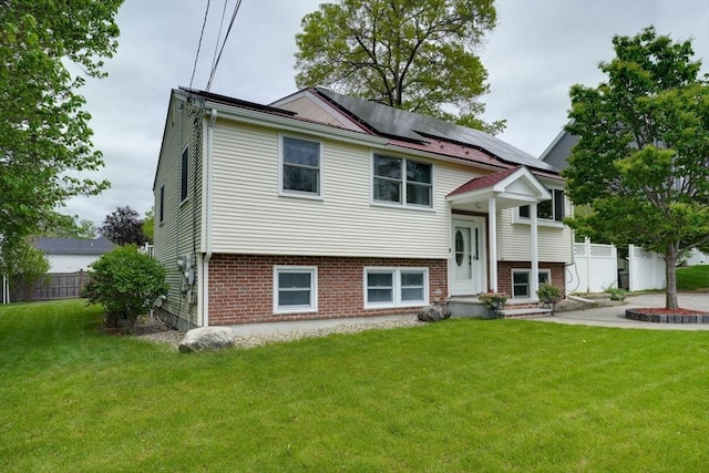 bi-level home featuring roof mounted solar panels and brick siding