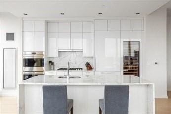 kitchen with a center island with sink, light countertops, decorative backsplash, appliances with stainless steel finishes, and white cabinetry