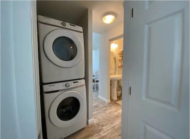 clothes washing area featuring stacked washer and clothes dryer and light hardwood / wood-style floors