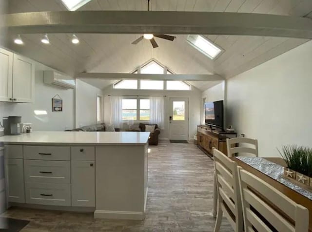 kitchen with lofted ceiling with beams, an AC wall unit, white cabinets, and kitchen peninsula