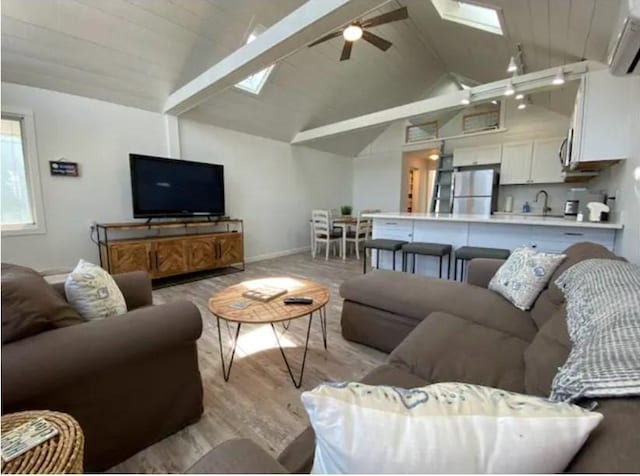 living room featuring light hardwood / wood-style flooring, lofted ceiling with skylight, and ceiling fan