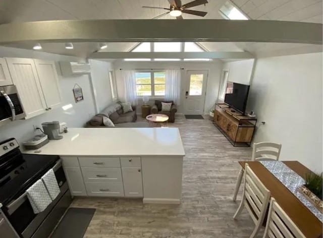 kitchen with appliances with stainless steel finishes, vaulted ceiling with beams, white cabinets, ceiling fan, and light hardwood / wood-style floors