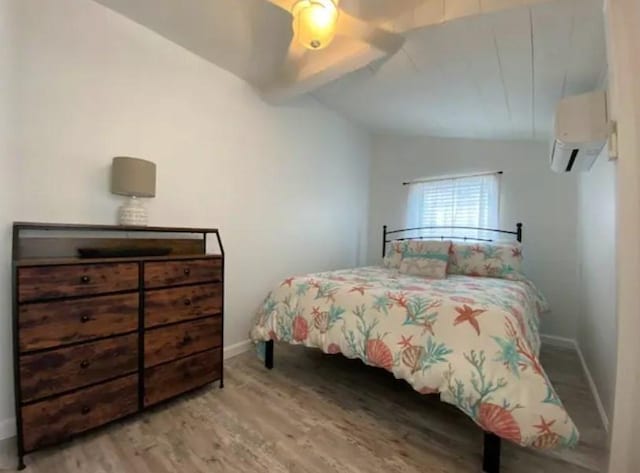 bedroom featuring an AC wall unit, vaulted ceiling with beams, and light wood-type flooring