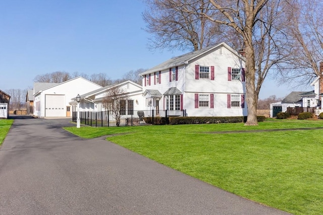 view of front of property featuring a front yard, fence, a residential view, and aphalt driveway