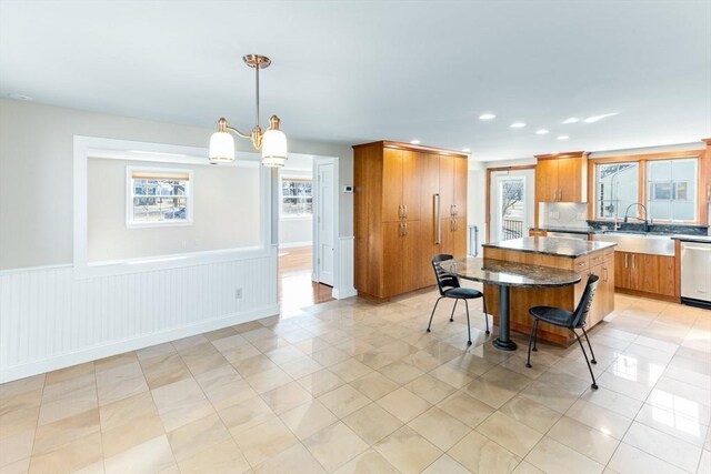 kitchen with a kitchen breakfast bar, plenty of natural light, a center island, and brown cabinetry
