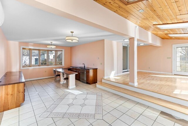kitchen featuring dark countertops, dishwasher, wood ceiling, light tile patterned flooring, and a sink