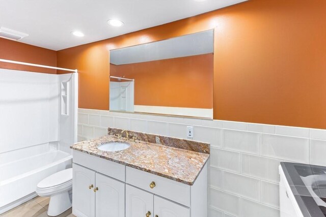 bathroom with vanity, tile walls, toilet, and shower / bathtub combination
