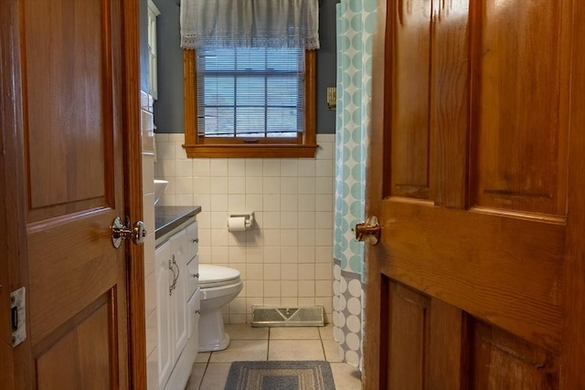 bathroom with tile patterned floors, toilet, vanity, and tile walls