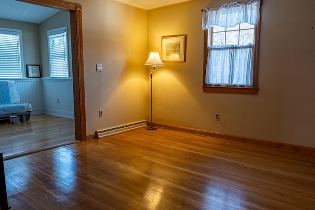 unfurnished room with a baseboard radiator and wood-type flooring