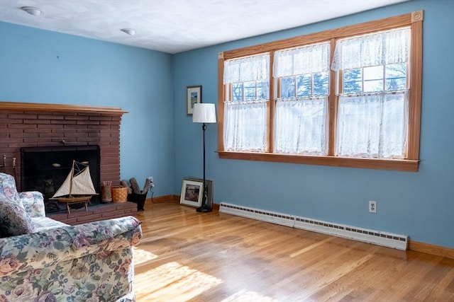 living room with a fireplace, a baseboard radiator, and light wood-type flooring