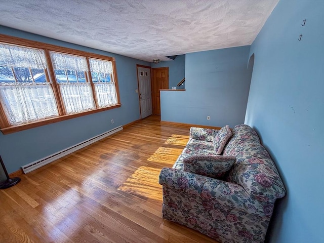 living area with light hardwood / wood-style floors, a textured ceiling, and a baseboard heating unit