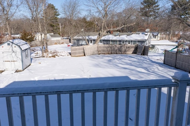 yard layered in snow featuring a storage shed