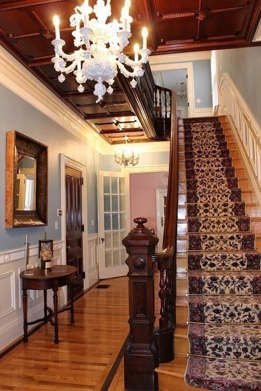 65 Central St, Andover, MA 01810 - stairs featuring a chandelier, ornamental molding, wood finished floors, a decorative wall, and coffered ceiling