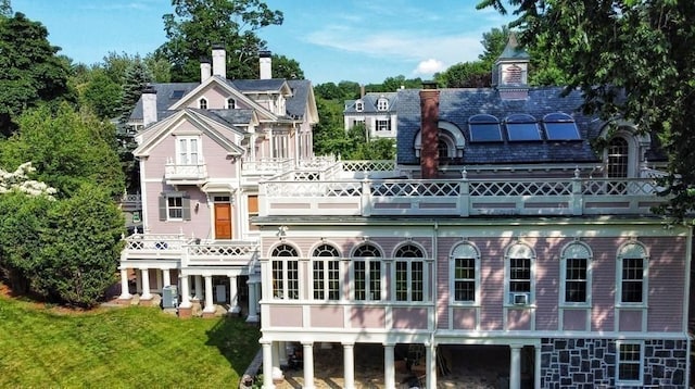 65 Central St, Andover, MA 01810 - back of house with a balcony, a chimney, a lawn, and solar panels