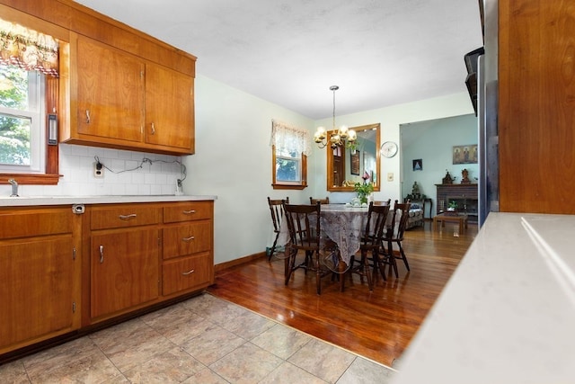 kitchen featuring pendant lighting, a chandelier, backsplash, and light hardwood / wood-style floors