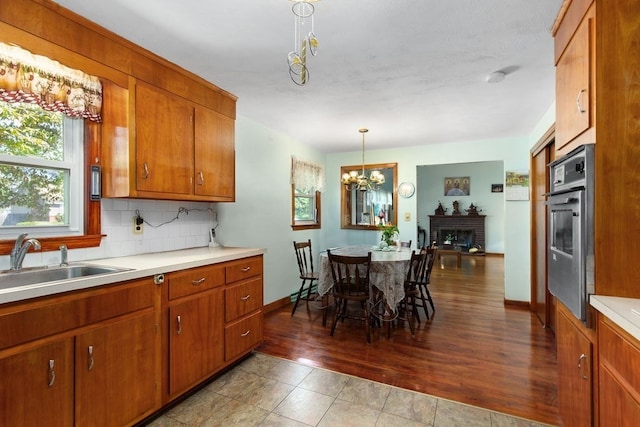 kitchen featuring a fireplace, a notable chandelier, hardwood / wood-style floors, backsplash, and stainless steel oven