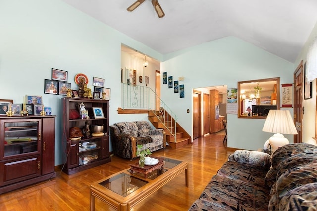 living room featuring lofted ceiling, ceiling fan with notable chandelier, and hardwood / wood-style flooring