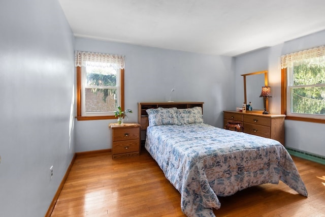 bedroom featuring hardwood / wood-style floors and a baseboard heating unit