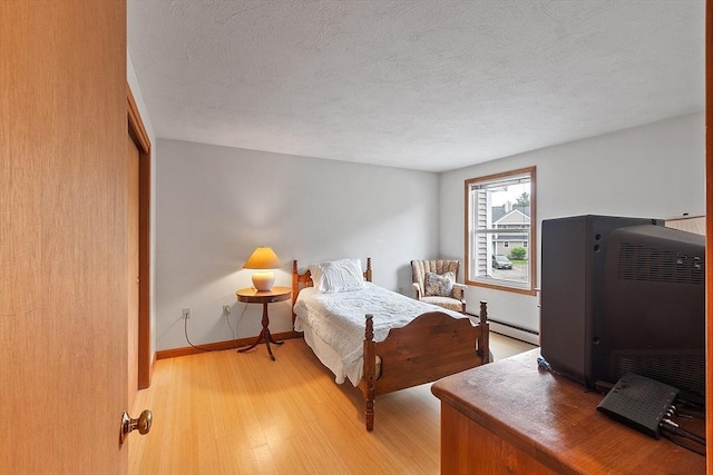 165 Bayberry Hill Ln Unit 165, Leominster, MA 01453 - bedroom with light wood finished floors, a textured ceiling, and a baseboard radiator