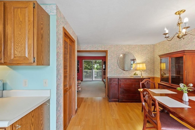 165 Bayberry Hill Ln Unit 165, Leominster, MA 01453 - dining area featuring light wood-style flooring, a chandelier, wallpapered walls, and a wainscoted wall