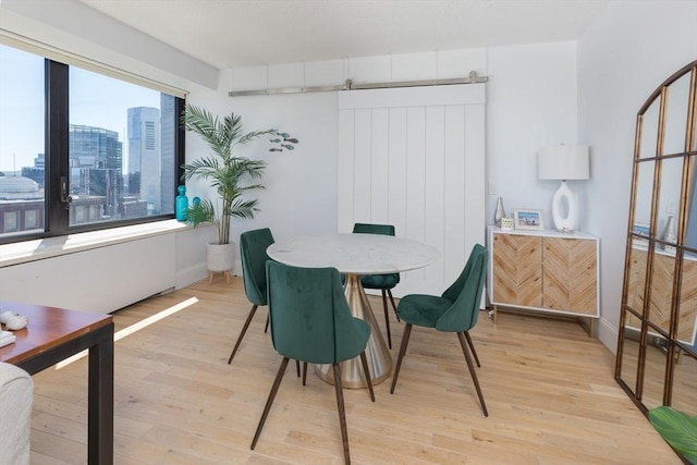 dining room featuring light wood-style flooring and a barn door