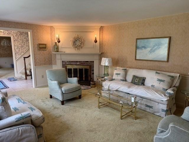 living area with wainscoting, wallpapered walls, light carpet, and a fireplace