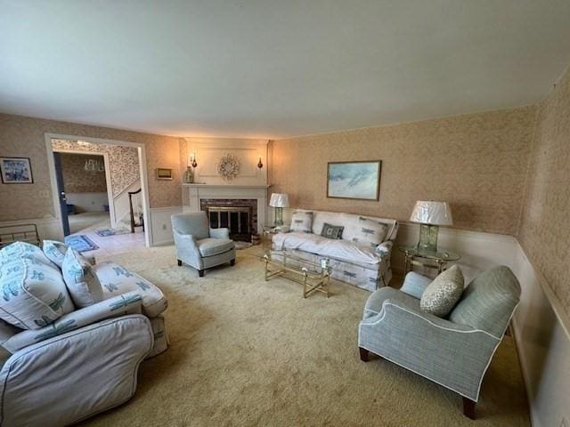 living room featuring a glass covered fireplace, a wainscoted wall, light carpet, and wallpapered walls