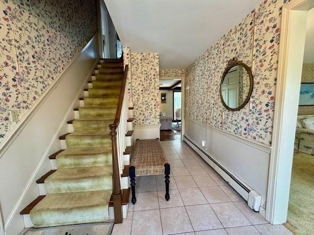 staircase featuring tile patterned flooring, a baseboard radiator, wainscoting, and wallpapered walls