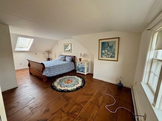 bedroom with wood-type flooring, baseboards, lofted ceiling with skylight, and baseboard heating