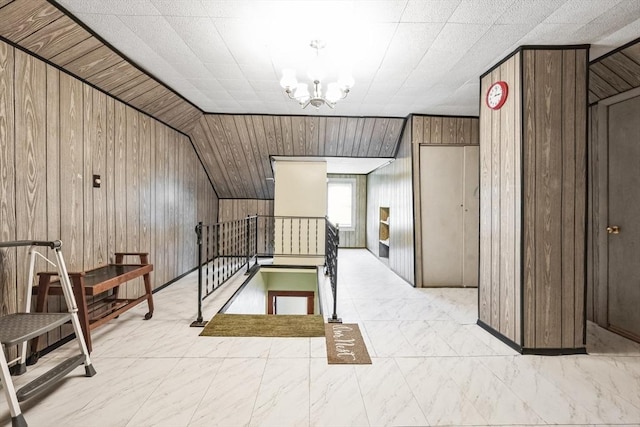 corridor featuring a chandelier, vaulted ceiling, and wooden walls