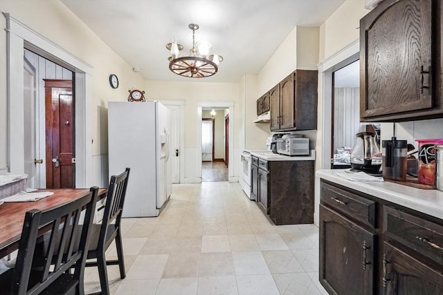 kitchen with white refrigerator with ice dispenser, range with electric cooktop, a chandelier, and dark brown cabinetry