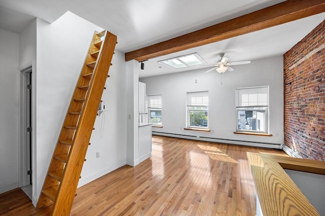 31 Division St # 3, Chelsea, MA 02150 - unfurnished living room featuring a baseboard radiator, beam ceiling, light wood-type flooring, a ceiling fan, and brick wall
