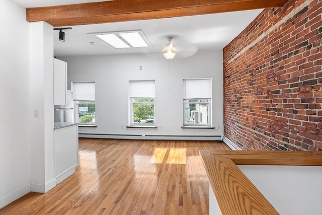 31 Division St # 3, Chelsea, MA 02150 - unfurnished living room with brick wall, light wood-style floors, ceiling fan, and baseboard heating