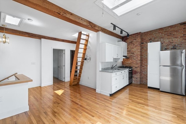 31 Division St # 3, Chelsea, MA 02150 - kitchen with stainless steel appliances, a skylight, light wood finished floors, brick wall, and white cabinets