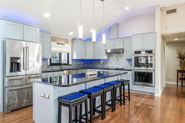 2171 Commonwealth Ave, Newton, MA 02466 - kitchen with appliances with stainless steel finishes, under cabinet range hood, dark countertops, backsplash, and a breakfast bar area