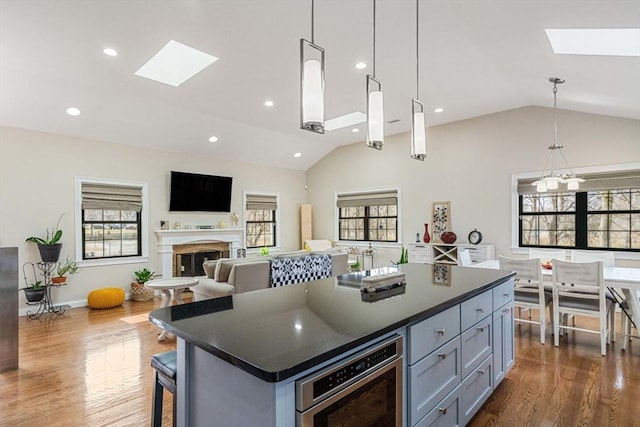 2171 Commonwealth Ave, Newton, MA 02466 - kitchen featuring a skylight, vaulted ceiling, dark countertops, a fireplace, and plenty of natural light