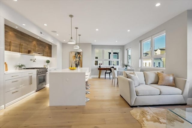 kitchen with light countertops, modern cabinets, open floor plan, and stainless steel range