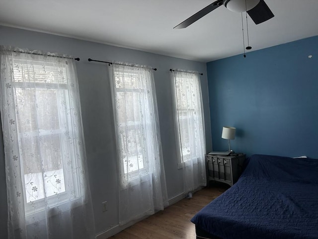 bedroom with multiple windows, wood finished floors, and ceiling fan