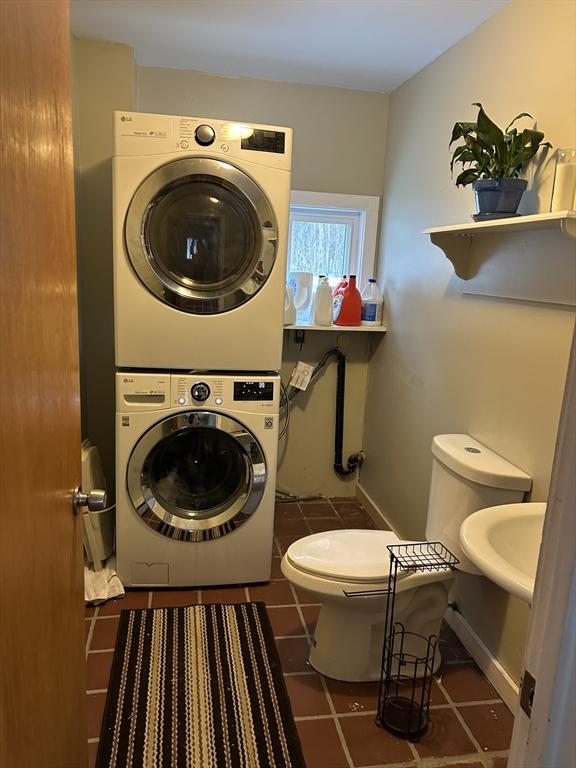 washroom with tile patterned flooring, laundry area, stacked washer and dryer, and baseboards