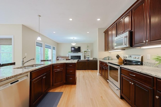 37 Sandy Ridge Rd, Sterling, MA 01564 - kitchen with appliances with stainless steel finishes, a sink, light wood-style flooring, hanging light fixtures, and a fireplace