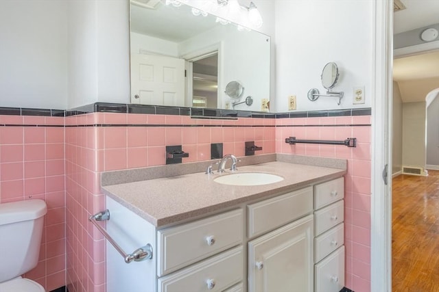 40 Fenimore Blvd, Springfield, MA 01108 - bathroom featuring tile walls, toilet, vanity, wood finished floors, and a wainscoted wall