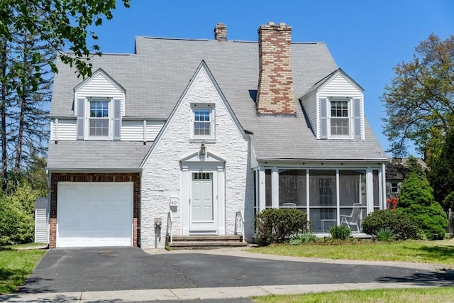 40 Fenimore Blvd, Springfield, MA 01108 - view of front of property with a sunroom, asphalt driveway, a garage, stone siding, and a chimney