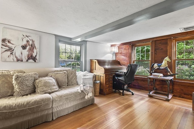home office featuring visible vents, a textured ceiling, wooden walls, and wood-type flooring