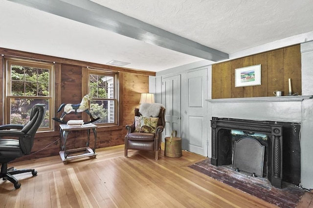 office with wooden walls, visible vents, beamed ceiling, hardwood / wood-style flooring, and a textured ceiling