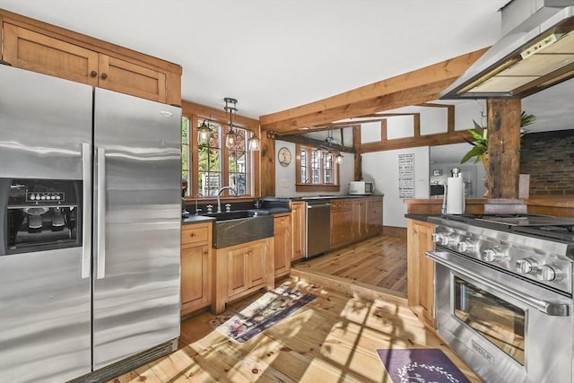 kitchen featuring a sink, stainless steel appliances, extractor fan, light wood-style floors, and dark countertops