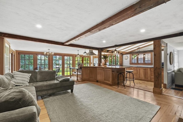 living room featuring a chandelier, beam ceiling, a textured ceiling, and light wood-style floors