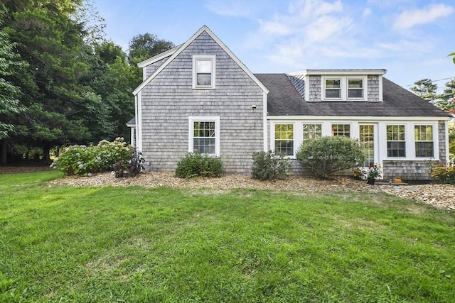 view of front facade with roof with shingles and a front yard