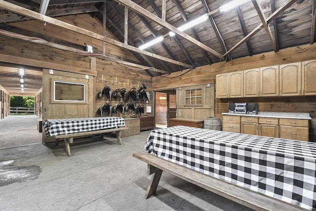bedroom with wooden walls, concrete floors, and high vaulted ceiling