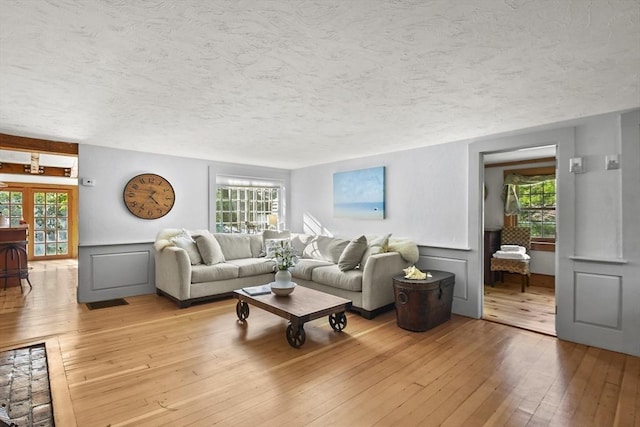 living room with a decorative wall, light wood finished floors, and a textured ceiling