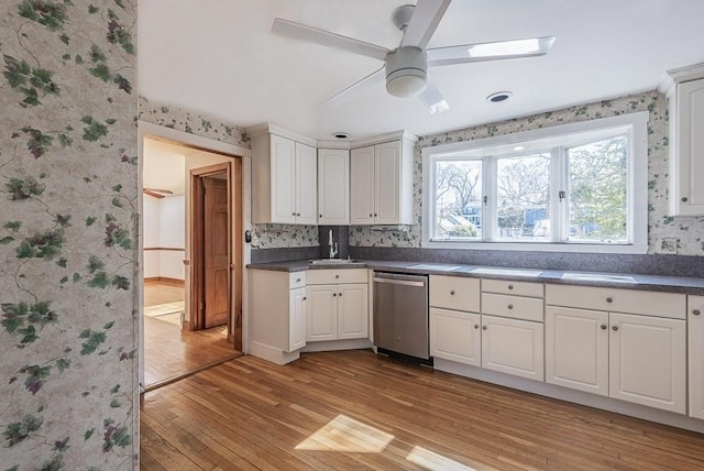 kitchen with dark countertops, dishwasher, light wood finished floors, and wallpapered walls